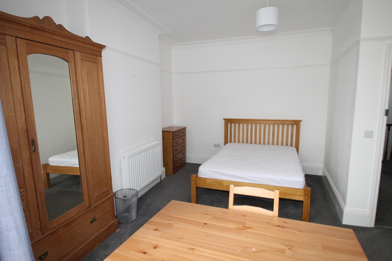 student bedroom with double bed, three door wardrobe with full length mirror, chest of drawers and desk with chair