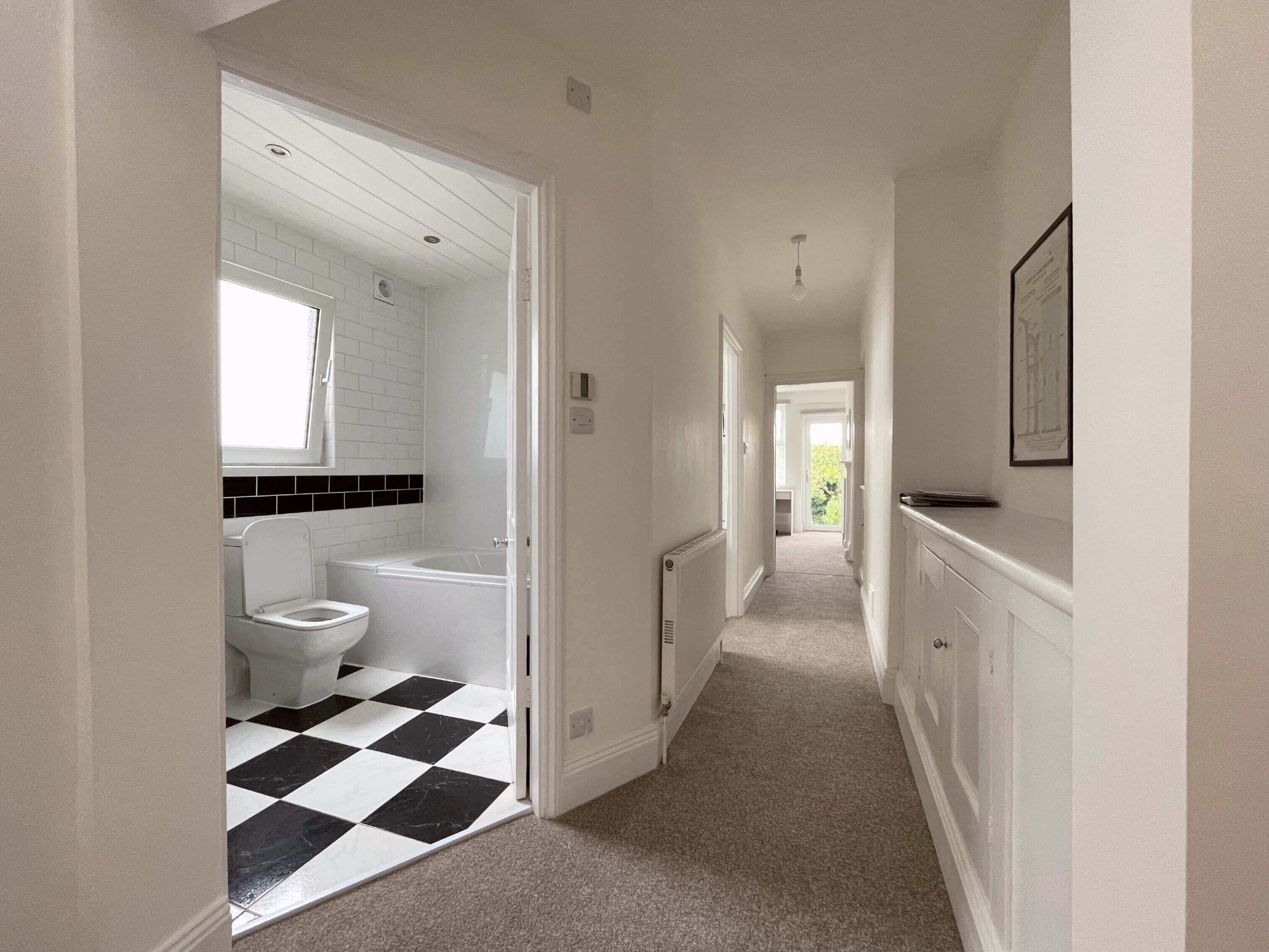Hallway of property showing entrance to bathroom and leading into living area
